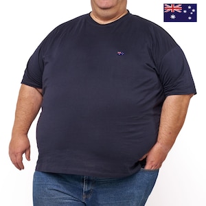 Puede incluir: Una camiseta de manga corta de color azul marino oscuro con una pequeña bandera australiana bordada en el pecho izquierdo. La camiseta se combina con pantalones vaqueros azules. La bandera australiana también aparece en la esquina superior derecha.