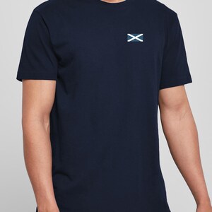 Op de afbeelding: Marineblauw T-shirt met een klein wit en blauw embleem op de linkerborst. Het shirt met korte mouwen is gemaakt van een zacht materiaal en heeft een ronde hals.