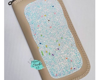 May include: A beige leather wallet with a zipper closure. The front of the wallet features a white, glittery design with colorful sprinkles.