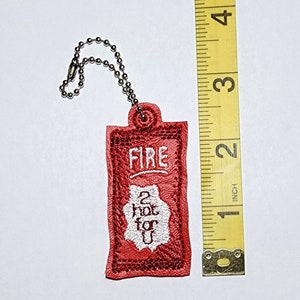 Puede incluir: Llavero de cuero rojo con un dise&ntilde;o bordado en blanco que dice "FIRE 2 hot for u".