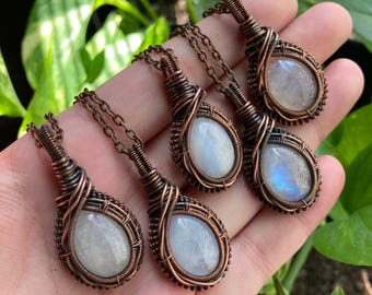 May include: Five copper wire wrapped pendants with moonstone stones. Each pendant is a teardrop shape with a copper wire design.