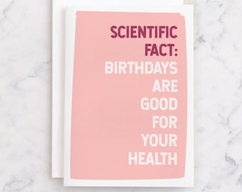 May include: A pink card with the text "SCIENTIFIC FACT: BIRTHDAYS ARE GOOD FOR YOUR HEALTH" in white letters with a burgundy outline.