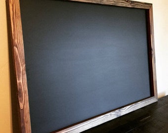May include: A black chalkboard with a dark brown wooden frame. The frame has a rustic, distressed look.