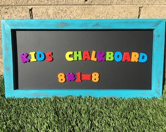 May include: A turquoise framed chalkboard with the words "KIDS CHALKBOARD" and the equation "8 x 1 = 8" spelled out in colorful magnetic letters.