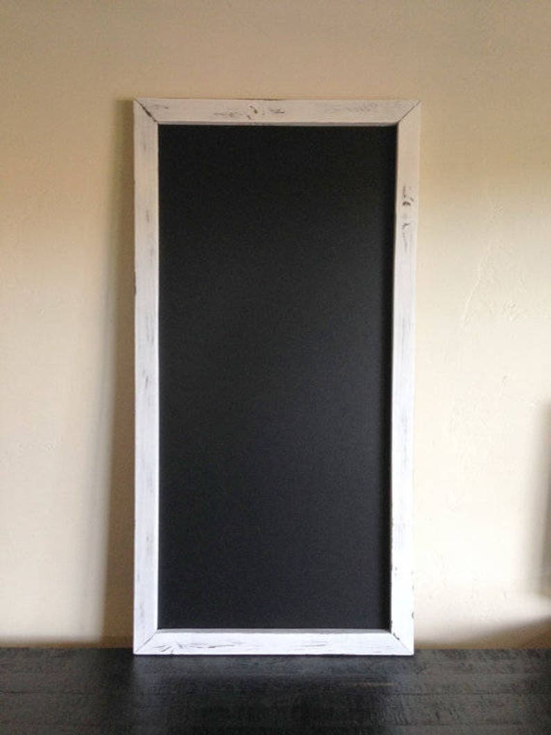 K&ouml;nnte beinhalten: Eine wei&szlig;e gerahmte Tafel mit einer schwarzen Oberfl&auml;che. Der Rahmen hat einen abgenutzten Look mit wei&szlig;er Farbe.