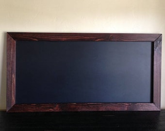 Könnte beinhalten: Eine rechteckige Tafel mit einer dunkelblauen Oberfläche und einem gebeizten, dunkelbraunen Holzrahmen. Der Rahmen hat sichtbare Holzmaserung und Knoten. Die Tafel wird vor einer neutralfarbenen Wand präsentiert.
