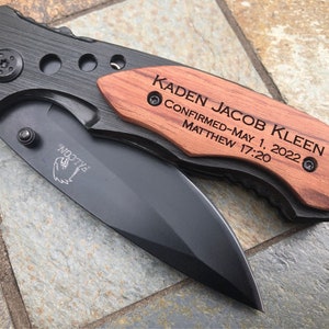 May include: A black pocket knife with a wooden handle engraved with the text "Kaden Jacob Kleen Confirmed-May 1, 2022 Matthew 17:20".