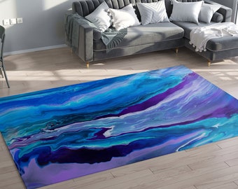 May include: Abstract area rug with blue, purple and white swirling patterns. The rug is on a hardwood floor in a living room setting.