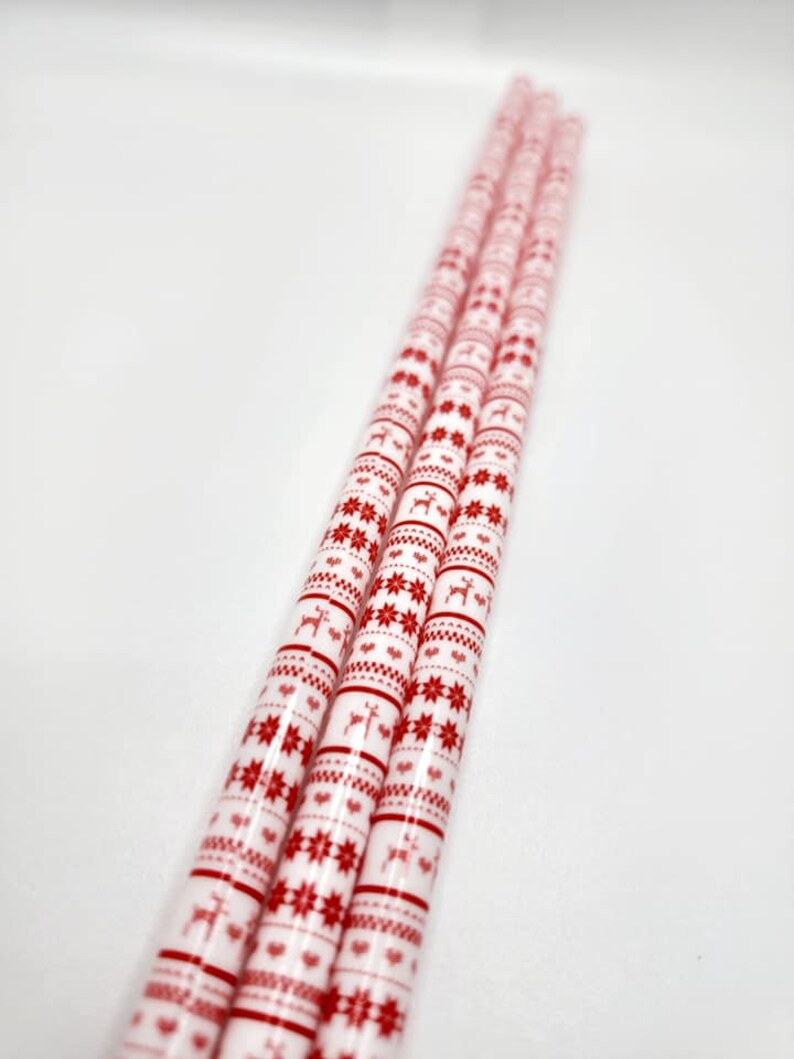 May include: Three white wrapping paper rolls with a red and white Christmas pattern featuring snowflakes, reindeer, and hearts.