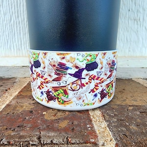 May include: A black planter with a white band featuring a Harry Potter themed pattern. The pattern includes owls, glasses, wands, and other Harry Potter symbols.