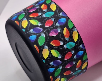 Può includere: Un bicchiere rosa con un coperchio nero e un motivo di luci natalizie colorate attorno al bordo.