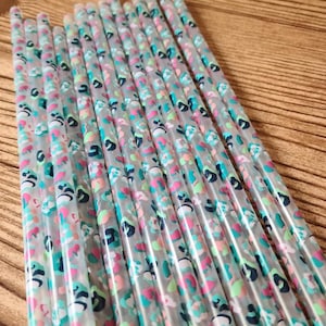 May include: A bundle of clear plastic drinking straws with a colorful abstract print. The straws are approximately 8 inches long and have a diameter of about 0.25 inches.