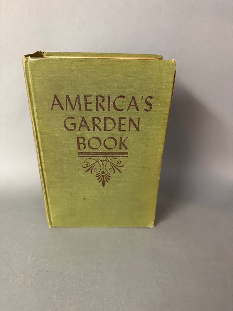 May include: A green hardcover book with the title "America's Garden Book" printed in brown lettering. The book has a decorative design on the front cover.