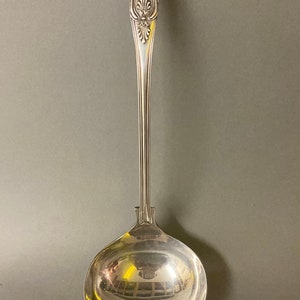 May include: A silver serving ladle with an ornate handle and a large, round bowl.