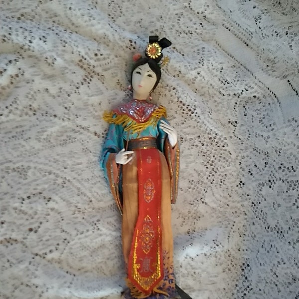 A Mandarin Brand Art Doll is a Geisha 15" tall doll from the 1950s. Traditional Chinese attire on a square stand.  Misc 1210