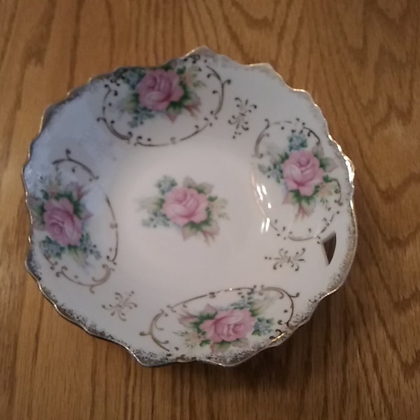 A Trimont Ware 7 inch wide bowl from Japan with a cut out near the rim, in a pink rose pattern with gold highlights and trim.  Bowl 1172