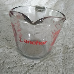 Anchor Hocking number 23 measuring cup that holds 16 oz or 2 cup measuring cup with red graphics. Dish 1186
