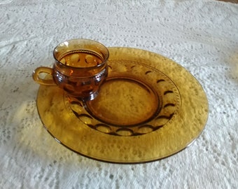 A matching pair of amber Kings Crown 2-10.5" luncheon plates with 2-7 oz footed cups in the thumbprint design with a loop handle.  Dish 1550