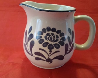 A vintage white stoneware creamer with a hand painted navy floral design and from at the rim.  Dish 998