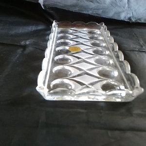 May include: A clear glass serving tray with a diamond pattern and scalloped edges. The tray has 12 individual indentations for holding small items.
