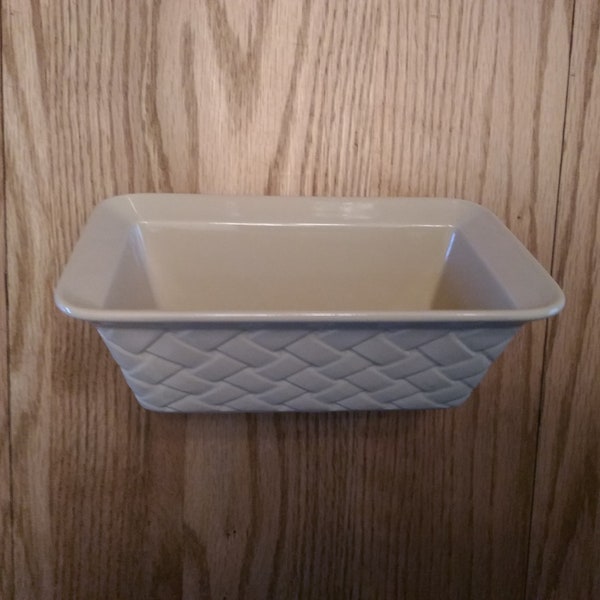 A Tastefully Simple cream colored loaf pan with a basket weave design on the outside.  It has a wide rim for easy handling.  SW 239