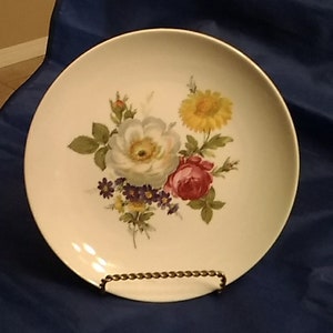 A 7.5&quot; Furstenberg blue backstamp white porcelain plate with a white and a pink rose with yellow and purple wildflowers.  Plate 633