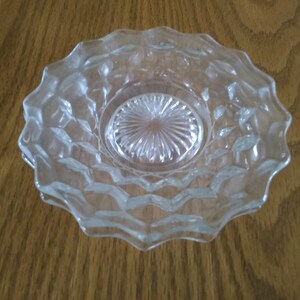 May include: Clear glass bowl with a diamond pattern on the sides and a starburst design in the center. The bowl has a scalloped edge and is likely used for serving or display.