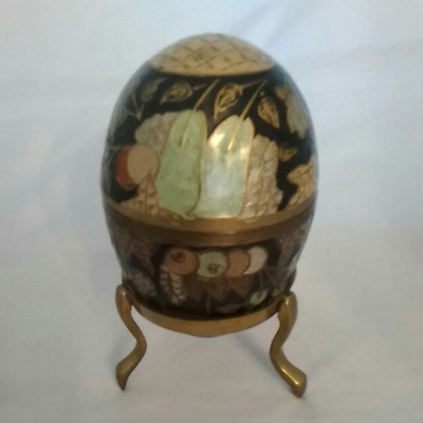 A two piece brightly hand painted brass egg on a brass three legged stand from India.  Misc 633