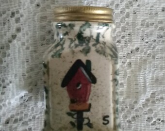 A Gibson ceramic salt shaker green sponge painted with a red bird house.  It has a gold toned screw on lid.  Dish 1181
