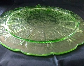 A Jeanette Glass uranium green depression glass footed cake plate in the Cherry Blossom pattern.  Plate 321
