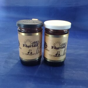 A Florida souvenir amber glass salt and pepper with a plastic lids, wooden handle, and a leather decorated band around each.  Dish 1100