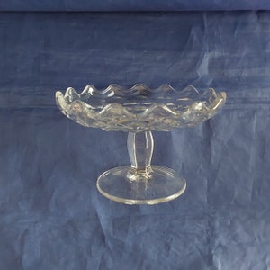 May include: A clear glass cake stand with a scalloped edge and a pedestal base.