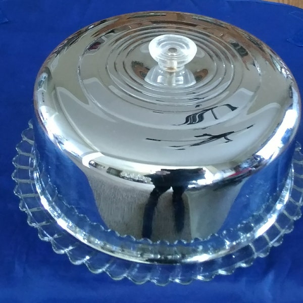 A Kromex and glass round cake saver.  The plate has three feet.  The chrome dome has the original clear knob handle.  Plate 704