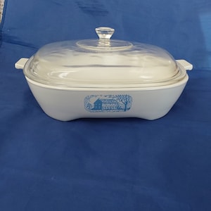 May include: White ceramic casserole dish with a blue and white winter scene design. The dish has a glass lid with a knob.