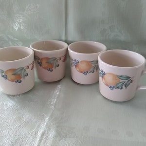 May include: Set of four white ceramic mugs with a lemon and leaf design. The mugs have a cream colored background with a green leaf and a yellow lemon design.