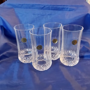 May include: Four clear glass tumblers with a diamond pattern. Each glass has a gold label with the text "Crystal  Luster" printed on it.