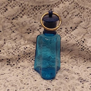 A late 1960s empty blue glass Windjammer cologne bottle with plastic lud and metal ring by Avon.  Misc 2017