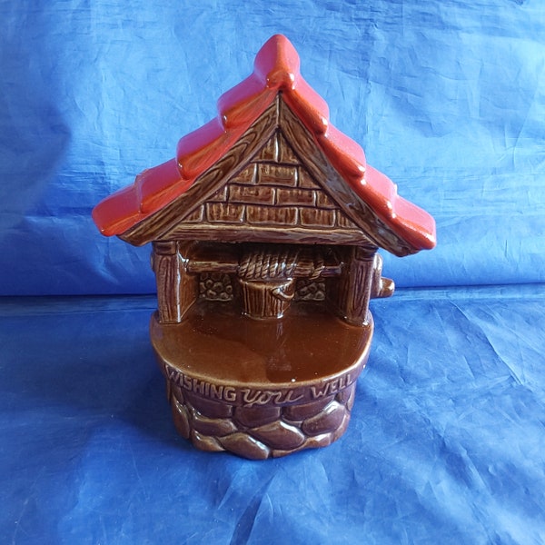 A McCoy Pottery USA planter that is a glazed brown stone well with a red shingled roof.  It reads "Wishing You Well".   SW  344