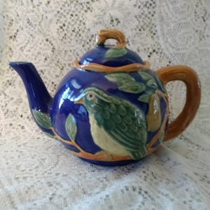 A Majolica teapot that is cobalt blue decorated with a green patridge in a pear tree.  CS. 225