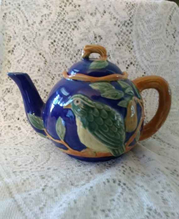 A Majolica Teapot That is Cobalt Blue Decorated With a Green
