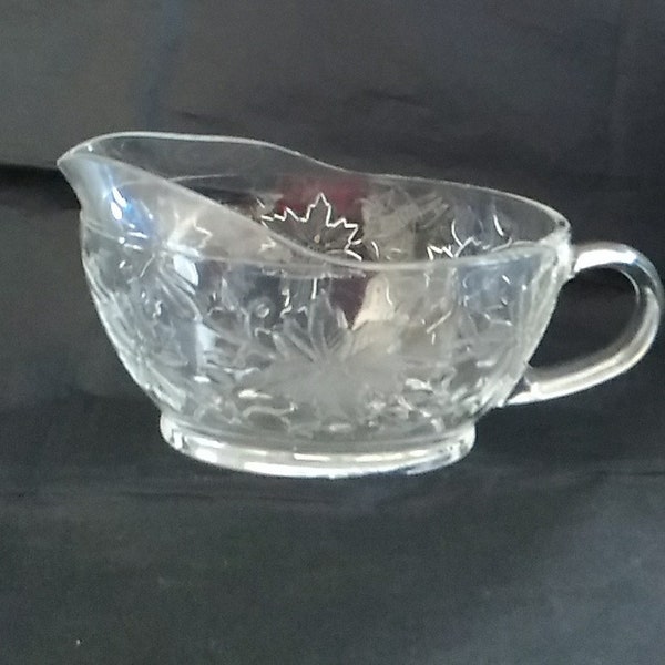 By Princess House, in their Fantasia pattern of Poinsettia flowers, is an oval clear gravy/ sauce boat dish with a handle.  Dish 1494