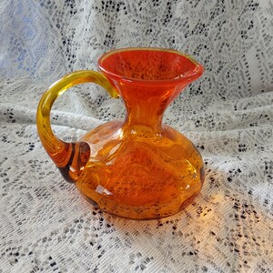 Amberina 5.5&quot; hand blown pitcher.  Starting with a yellow rim then tangerine fading to orange with a yellow applied glass handle.  Misc 1333