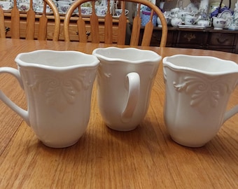 A set of 3-14 fluid ounce Lenox Butler's Pantry mugs that is an off white earthenware with a decorative rim.   DWS 788