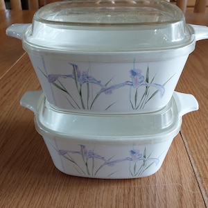 May include: A white ceramic mug with a black handle and the text "But First, Coffee" in a bold, black font. The mug is set against a blurred background, highlighting its clean design.