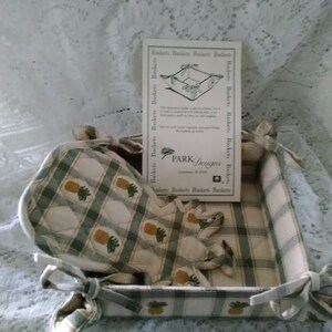 May include: A green and white checkered fabric bread basket with a matching green and white pot holder with a pineapple pattern. The basket has a tag that reads "PARK Designs, Gastonia, NC 28054".