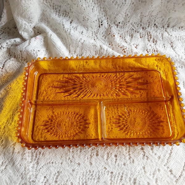 A Jeanette Glass rectangular shaped amber gold relish dish divided into 3 parts with a beaded trim and starburst design. Plate 897