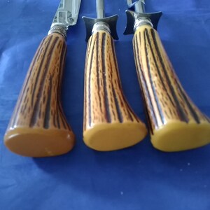 K&ouml;nnte beinhalten: Set aus drei Vintage-Steakmessern mit braunen und schwarzen Hirschhorn-Griffen. Die Griffe sind aus Kunststoff und haben eine gelbe Farbe.