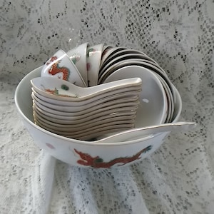 A 25 piece white porcelain Asian rice or noodle set with an orange and green dragon and a bird.  Bowl 1044
