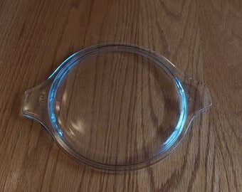 A clear round Pyrex glass lid with tab handles number 474-C. It has no chips or cracks.  It is a great replacement lid.  CD 179