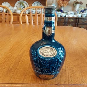 May include: A blue ceramic bottle of Royal Salute 21 year old blended Scotch whisky. The bottle has a gold label with the Royal Salute logo and the words "21 Years Old Blended Scotch Whisky".